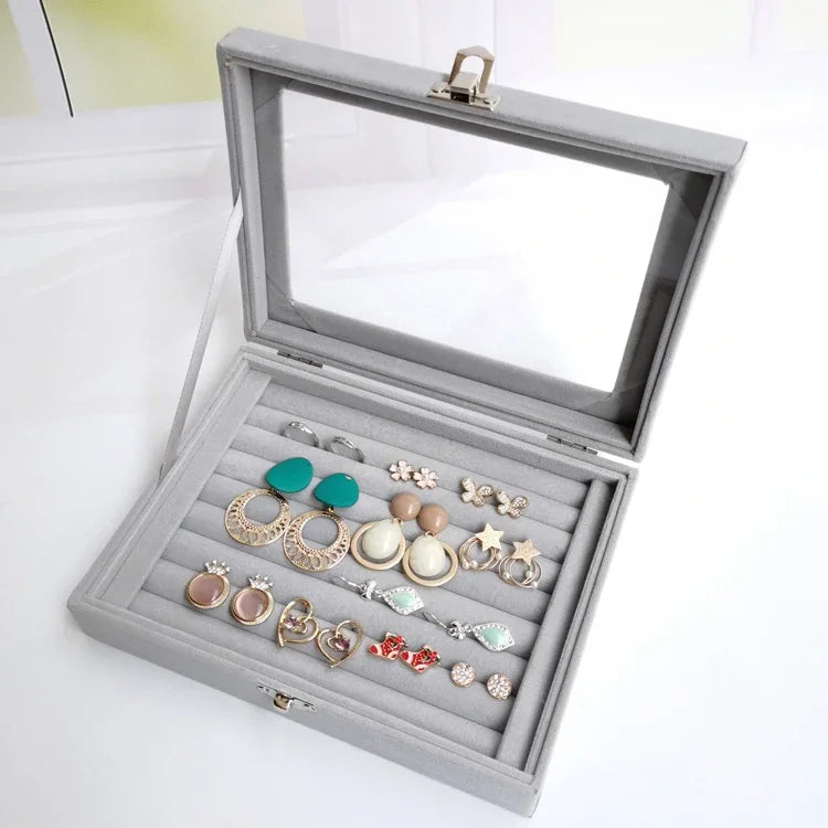 Gray velvet earring organizer box with transparent lid, featuring 7 horizontal slots neatly displaying various colorful earrings